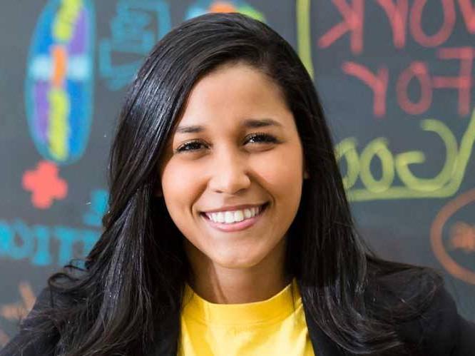 Business woman smiling for picture infront of colorful chalk board